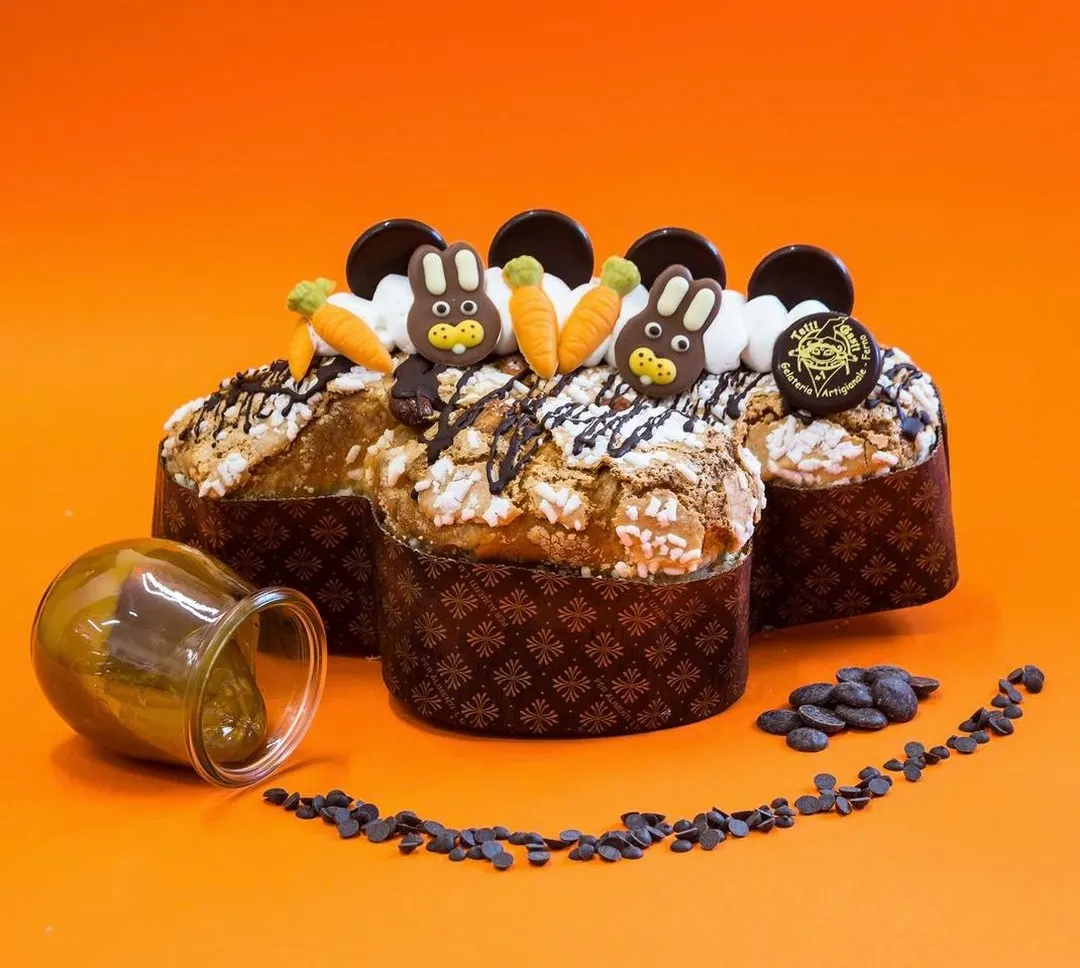 Colomba di Pasqua decorata con coniglietti e carote di zucchero, su fondo arancio